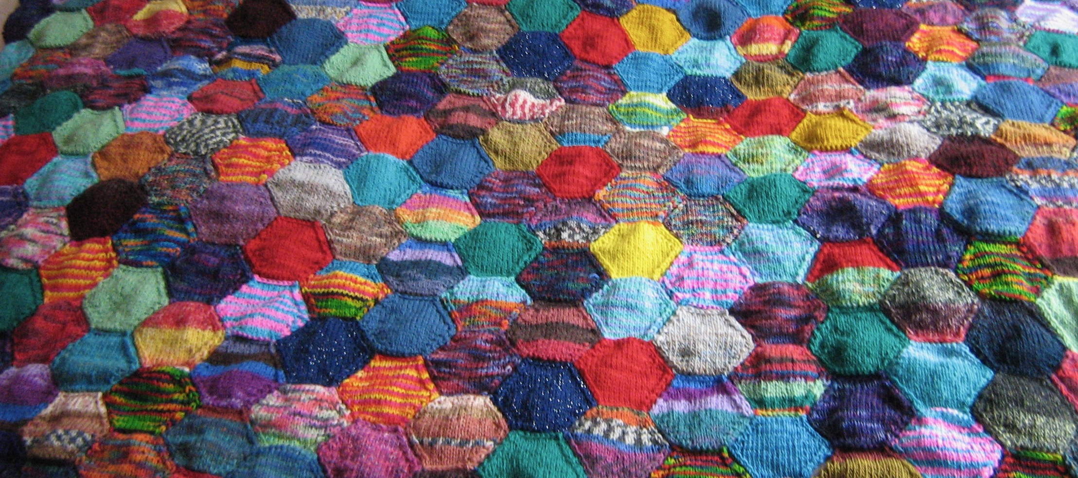 A close-up of knitted hexagons made from a random mix of leftover sock yarns