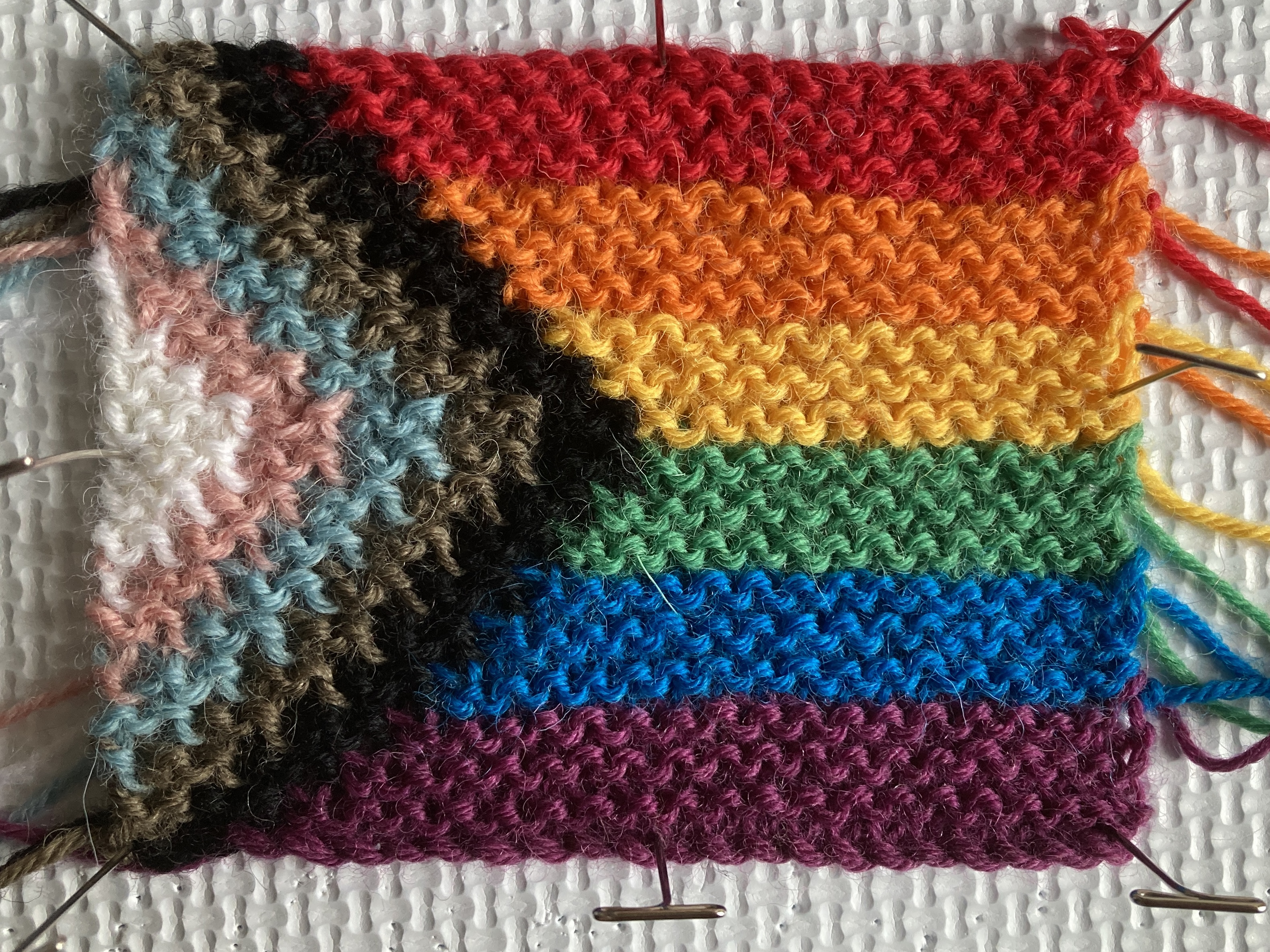 A progress pride flag knitted using garter stitch intarsia technique.