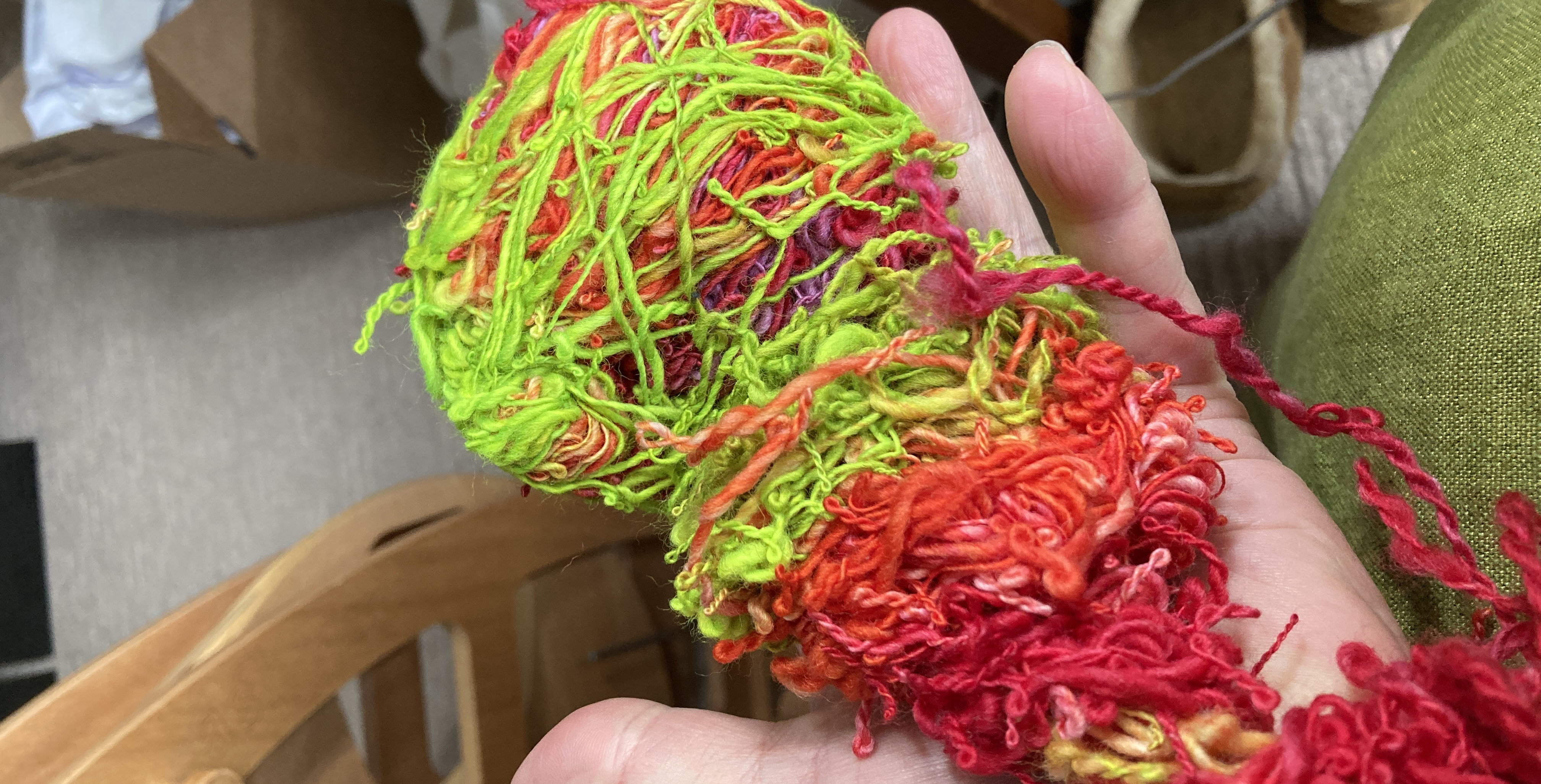 A very tangled and twisted mess of brightly coloured hand spun yarn held in my hand.